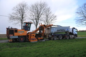 Bankettfräse lädt Erde in einen Kipplaster